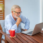 Senior man executive with white hair using computer laptop watch